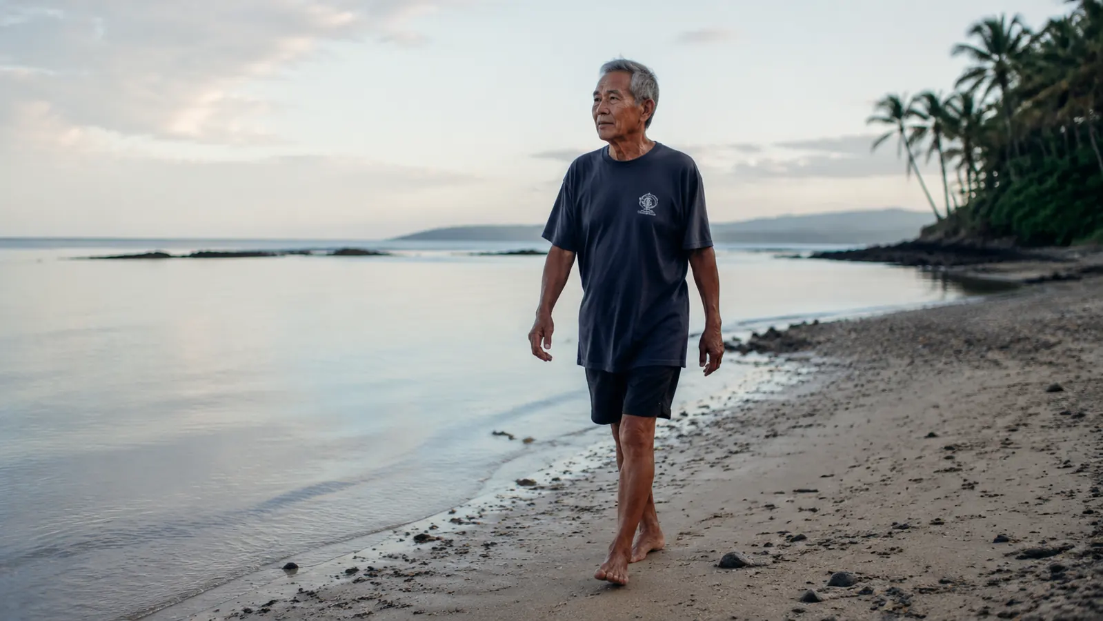 Older man walking slowly on a beach at low tide, bare feet on wet sand, facing the ocean