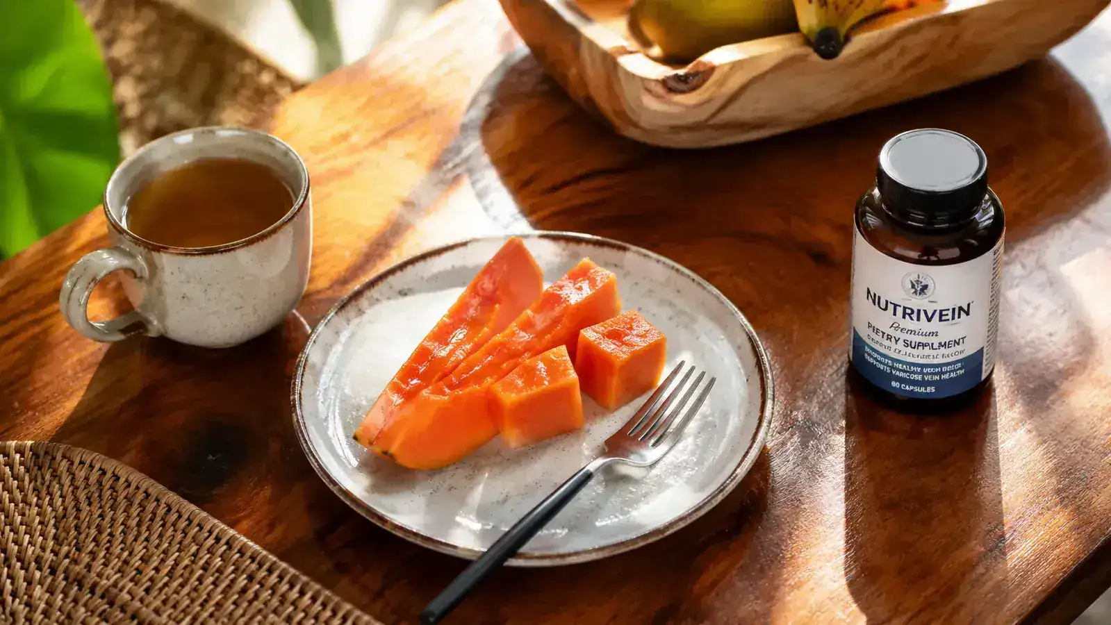 A simple wooden table set with a cup of tea, a small bowl of fruit, and a capsule bottle in soft morning light
